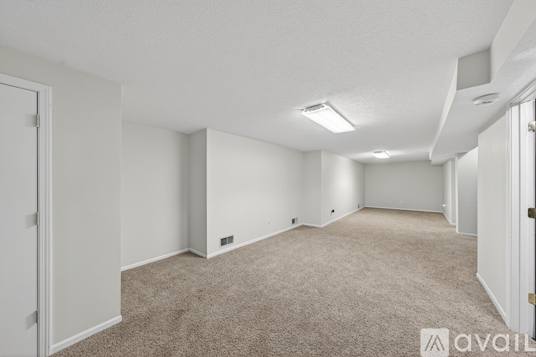 A spacious room with carpeted floor and white walls.