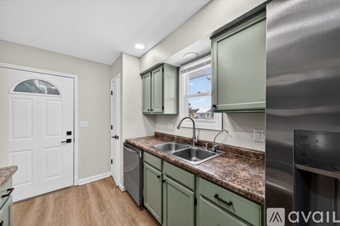 A kitchen with green cabinets and a stainless steel refrigerator.