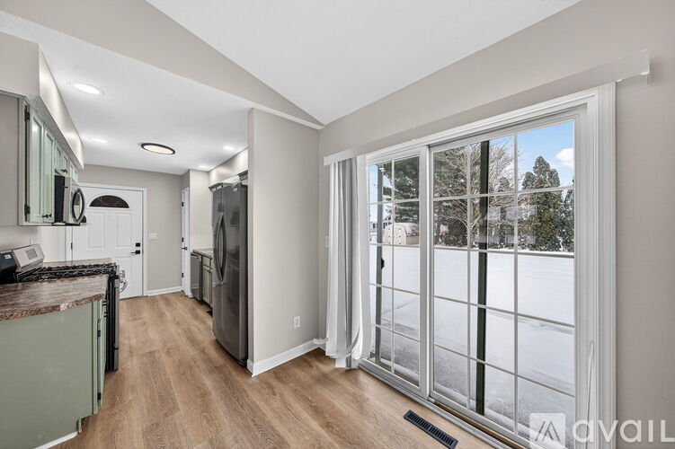 A kitchen with a refrigerator, sink, and a window with a view of trees.