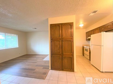 A kitchen area with a white refrigerator and wooden door.