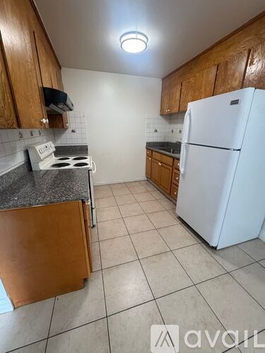 A kitchen with a white fridge, stove and wooden cabinets.