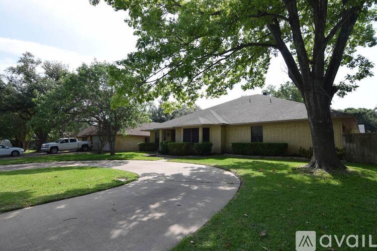A house with a driveway and a tree in front of it.