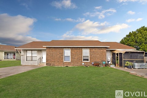 A house with a brown roof and a green lawn in front.