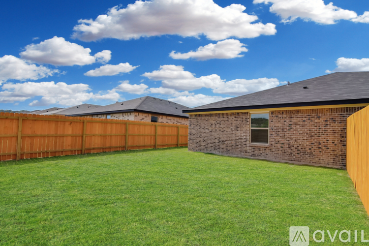 A backyard with a wooden fence and a grassy area.