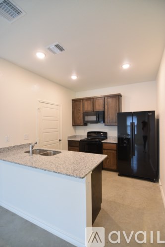 A kitchen with a granite countertop and a black refrigerator.