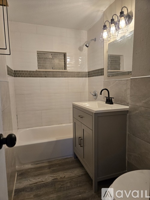 A bathroom with a white tiled shower and a white sink.