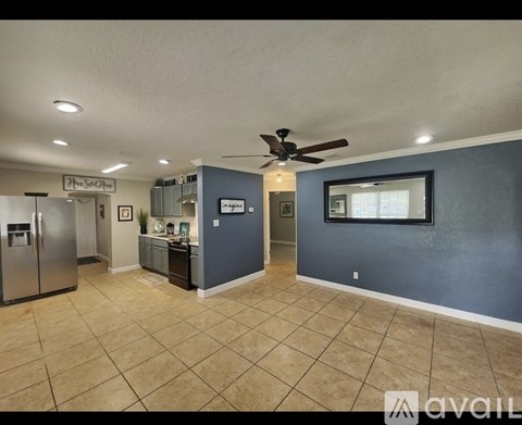 A kitchen area with a refrigerator, cabinets, and a ceiling fan.