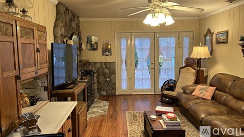 A living room with a brown leather couch and a wooden cabinet.