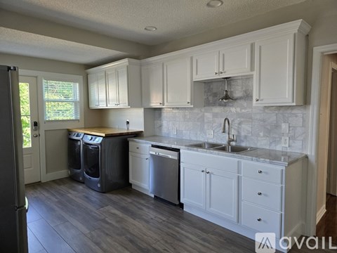 A kitchen with white cabinets and a marble backsplash.