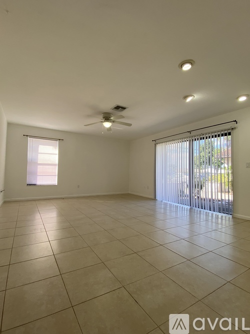 A spacious room with a ceiling fan and sliding glass doors.
