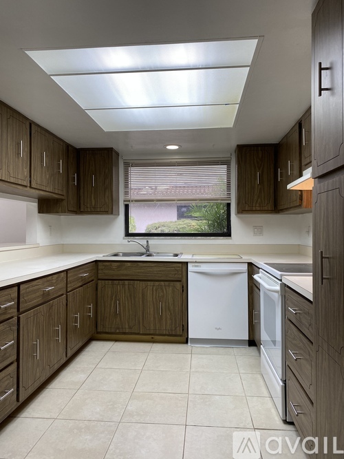 A kitchen with brown cabinets and a white dishwasher.