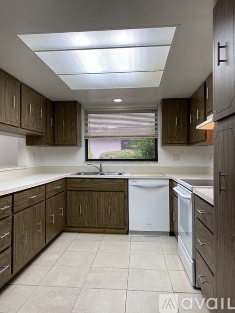 A kitchen with brown cabinets and a white dishwasher.