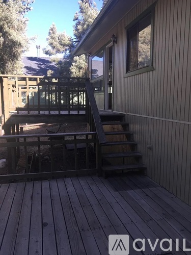 A room with wooden flooring and a window with a view of trees outside.