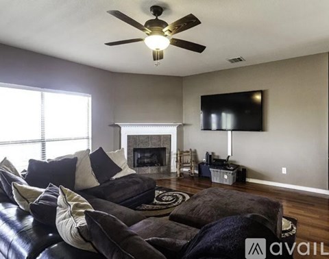 A living room with a black couch and a fireplace.