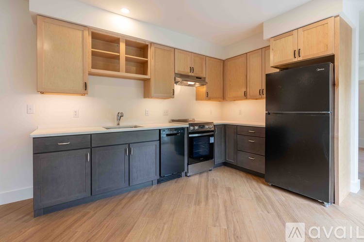 A kitchen with wooden cabinets and a black refrigerator.