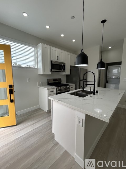 A modern kitchen with a yellow door and white countertops.