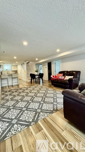 A living room with a patterned rug and a brown leather couch.