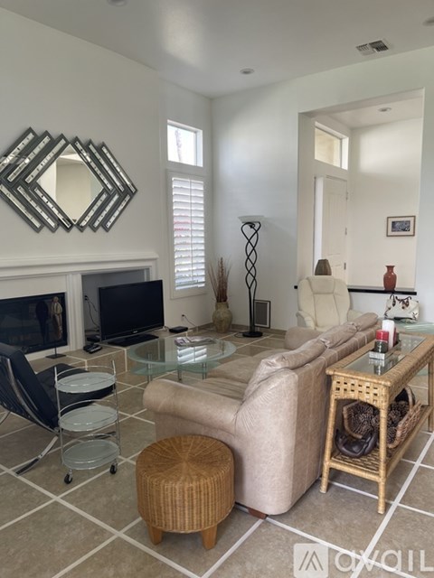 A living room with a glass coffee table and a beige couch.