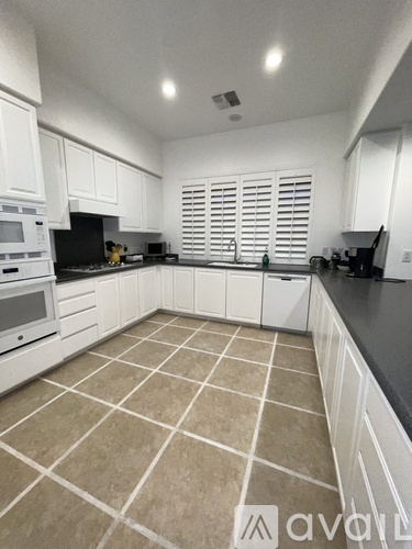 A kitchen with white cabinets and a tiled floor.