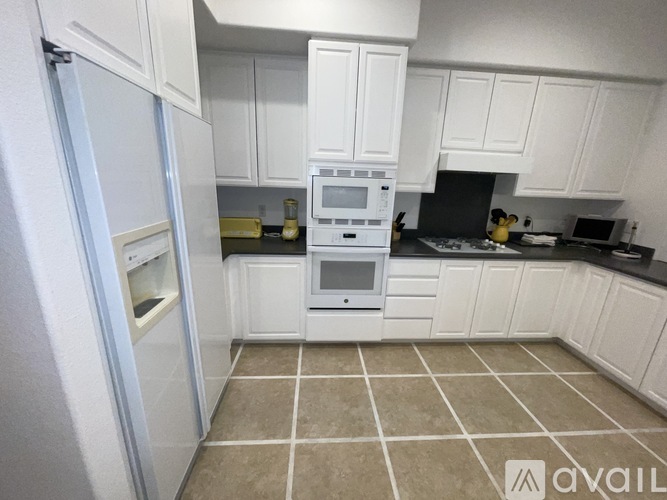 A kitchen with white cabinets and a tiled floor.