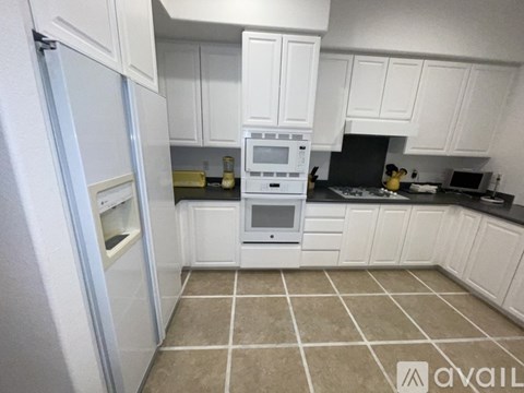 A kitchen with white cabinets and a tiled floor.