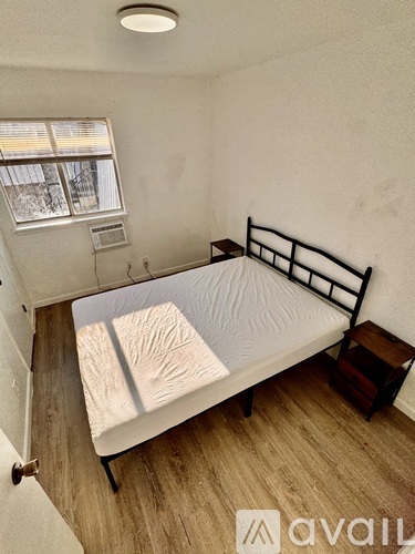 A bedroom with a bed, nightstand, and window.
