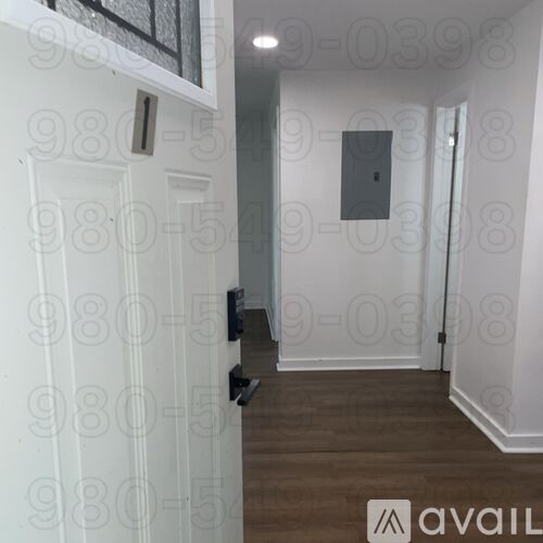 A hallway with a white door and a wall-mounted TV.