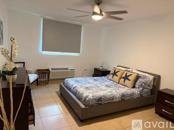 A bedroom with a bed, a dresser, and a ceiling fan.