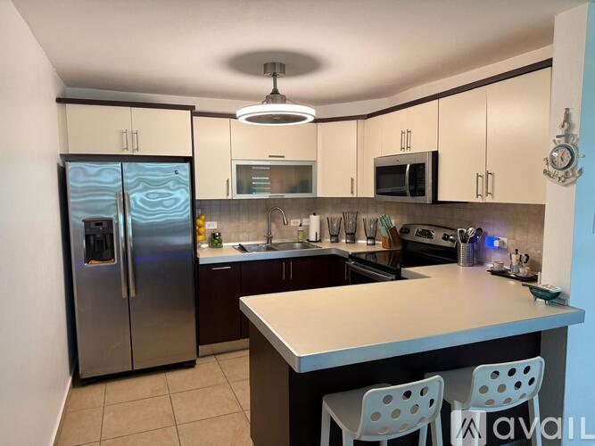 A kitchen with a refrigerator, microwave, oven, and sink.