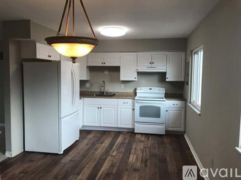 A kitchen with white appliances and wooden floors.