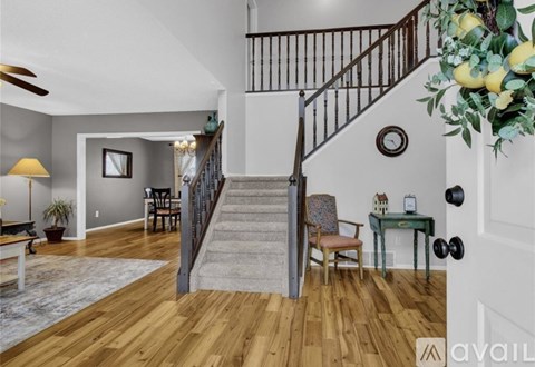 A living room with a staircase and a table with a plant on it.
