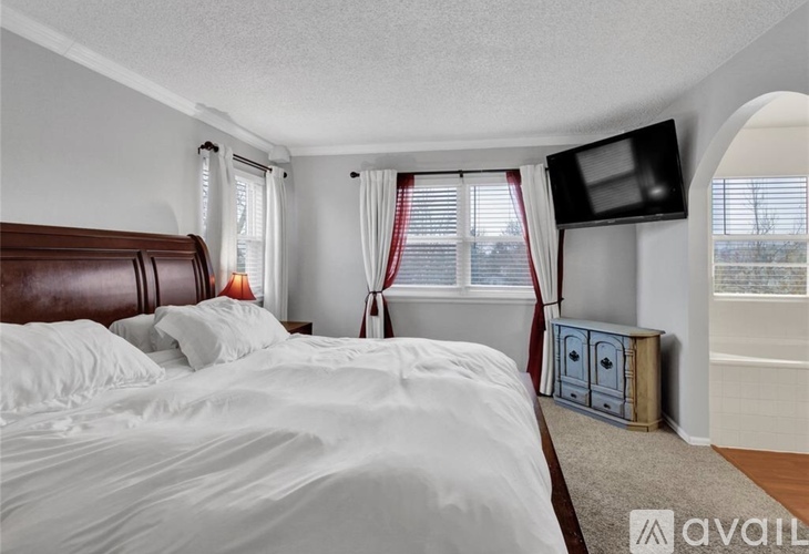 A bedroom with a large bed and a flat screen TV mounted on the wall.