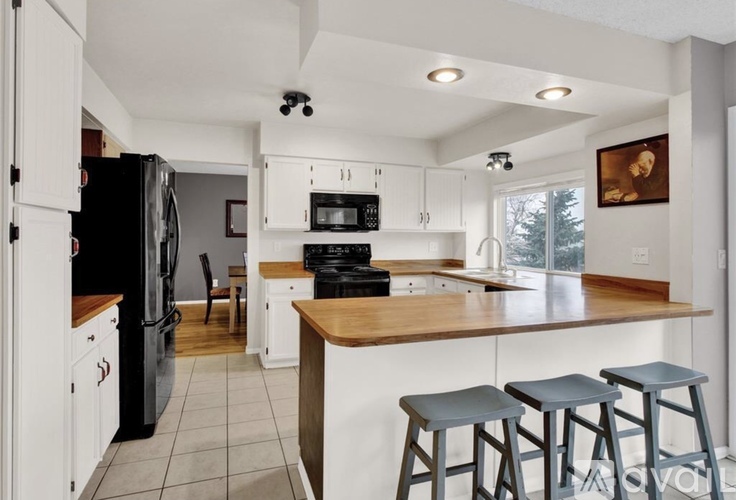 A kitchen with white cabinets and a black fridge.