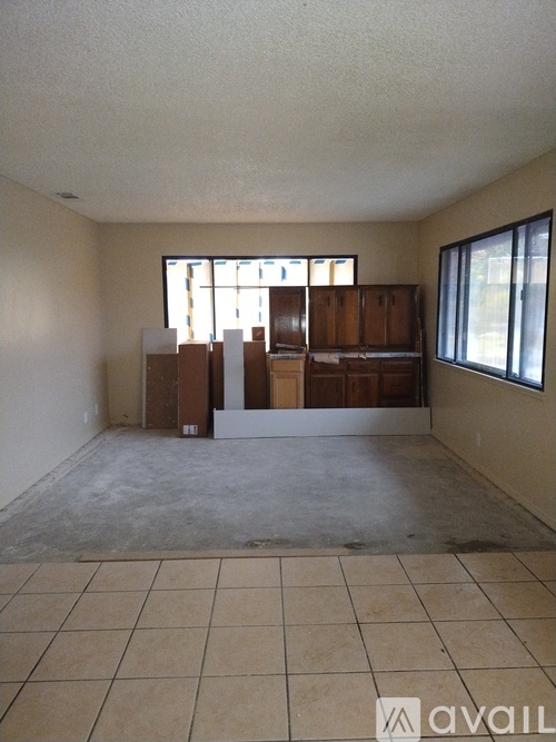 Empty room with tiled floor and large windows.