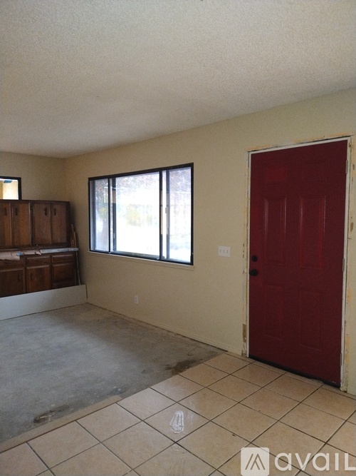 A room with a red door and a window with blinds.