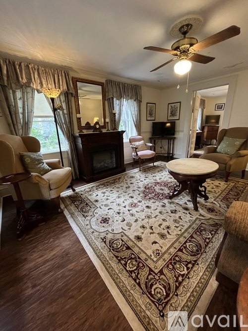 A living room with a rug, a chair, a table, a television, and a fan.