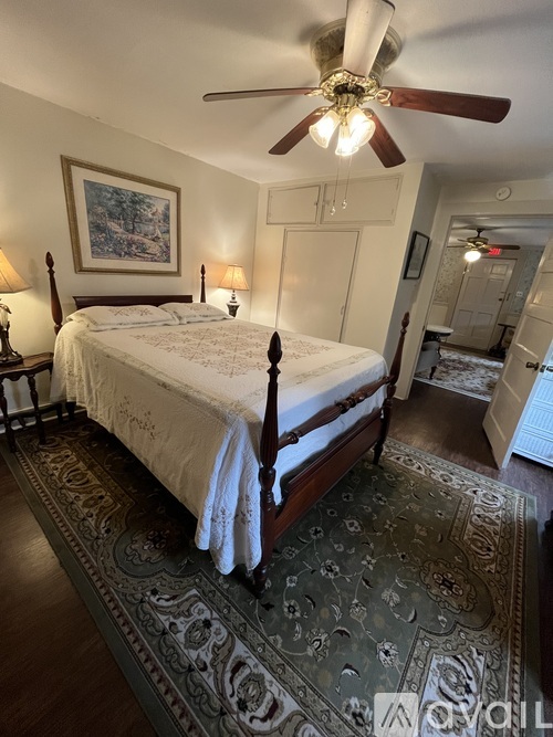 A bedroom with a large bed and a ceiling fan.
