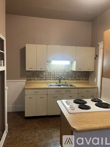 A kitchen with white cabinets and a wooden island.