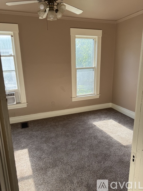A room with a carpeted floor and a ceiling fan.