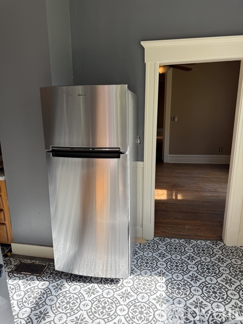 A silver fridge in a room with a tiled floor.