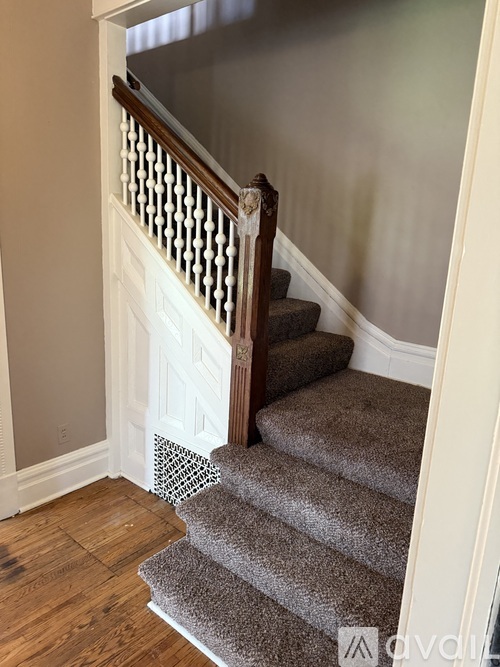 A staircase with a wooden banister and a carpeted runner.
