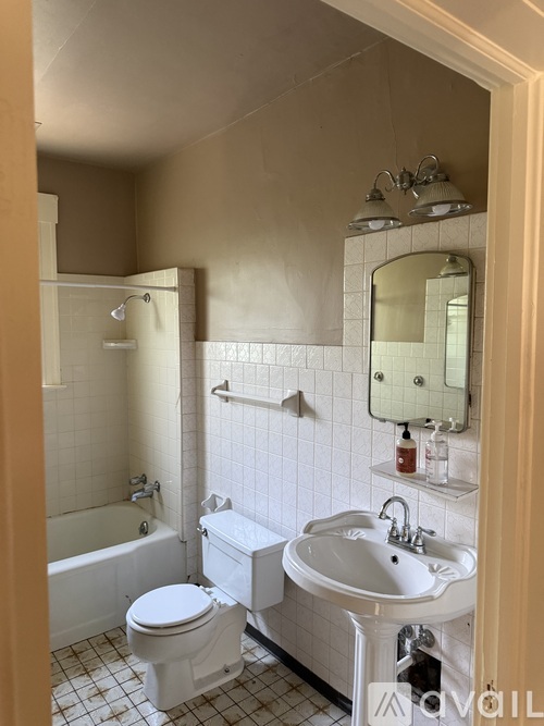 A white toilet is in a bathroom with a white sink and a white bathtub.