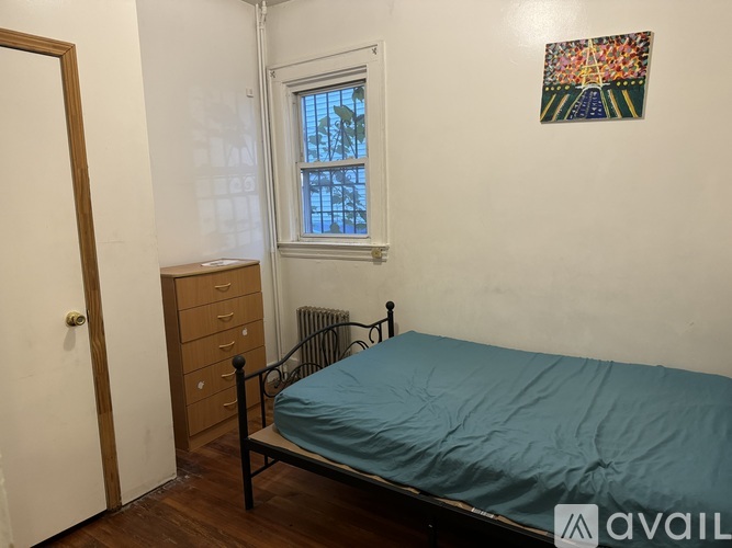 A bedroom with a bed, dresser, and window.