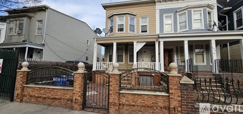 A house with a grey facade is in front of a house with a blue facade.