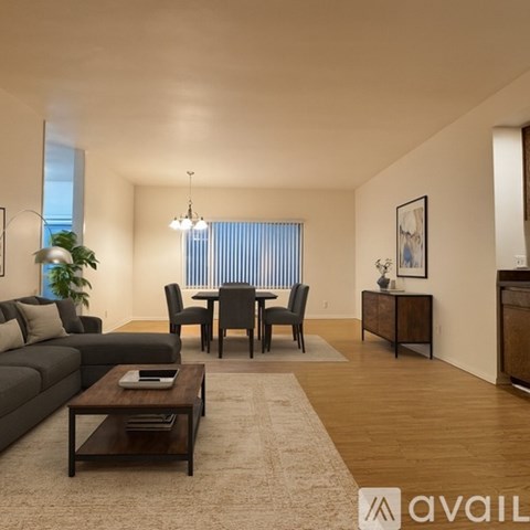 A living room with a grey couch, a brown coffee table, and a dining table with chairs.