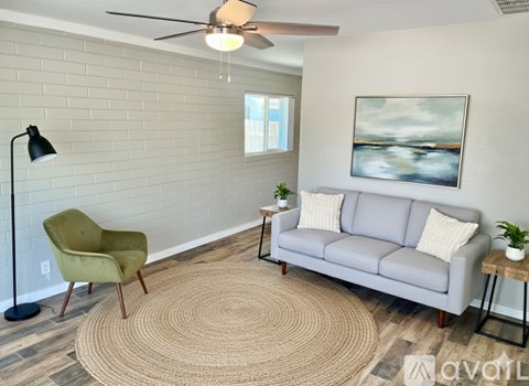 A living room with a grey couch, a green chair, and a painting on the wall.