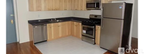 A kitchen with wooden cabinets and a stainless steel refrigerator.