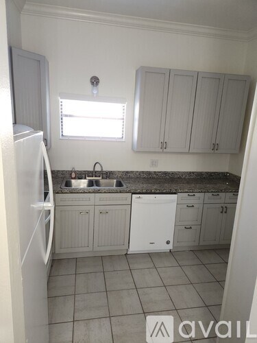 A kitchen with white cabinets and a white refrigerator.