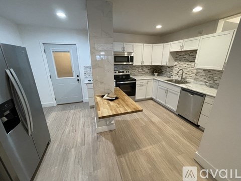 A modern kitchen with a wooden table and stainless steel appliances.