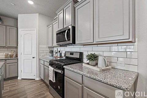 A kitchen with a granite countertop and a black microwave above it.